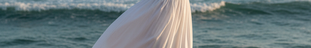 Blonde Woman Dancing on Beach in White Lace Dress
